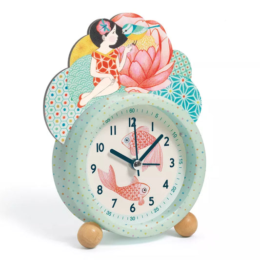 A Djeco Alarm Clocks Fish with a little girl sitting on top of it.