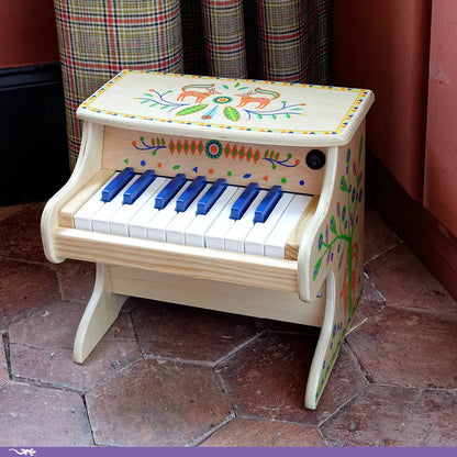 A Djeco Animambo Electronic Piano sitting on top of a tile floor.