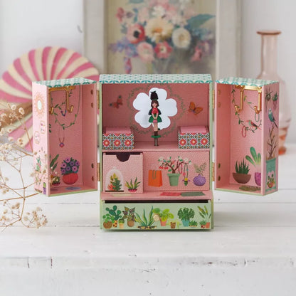 A Djeco Music Box Secret Garden with a doll inside of it.