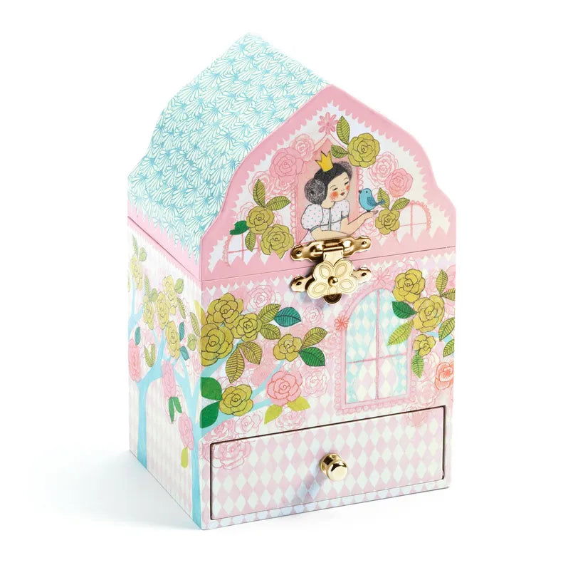 The Djeco Music Box Delighted Palace is a charming, pastel-colored jewelry box shaped like a small house. It is adorned with floral designs, a window illustration, and a vintage-style latch. The top features an illustration of a girl with a bird, enhancing its whimsical appeal. This princess-themed toy also includes a drawer with a small knob at the bottom for added storage.