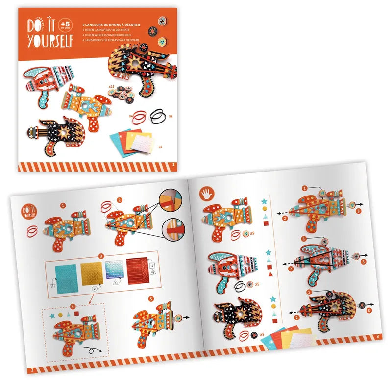 Image of an open guidebook from the Djeco Mosaics & Stickers Kosmik set, detailing steps on how to create a decorative elephant. The left page displays the cover featuring a completed elephant design, along with colored paper and crafting tools. The right page provides step-by-step illustrated instructions presented in a colorful and playful design using mosaic stickers.