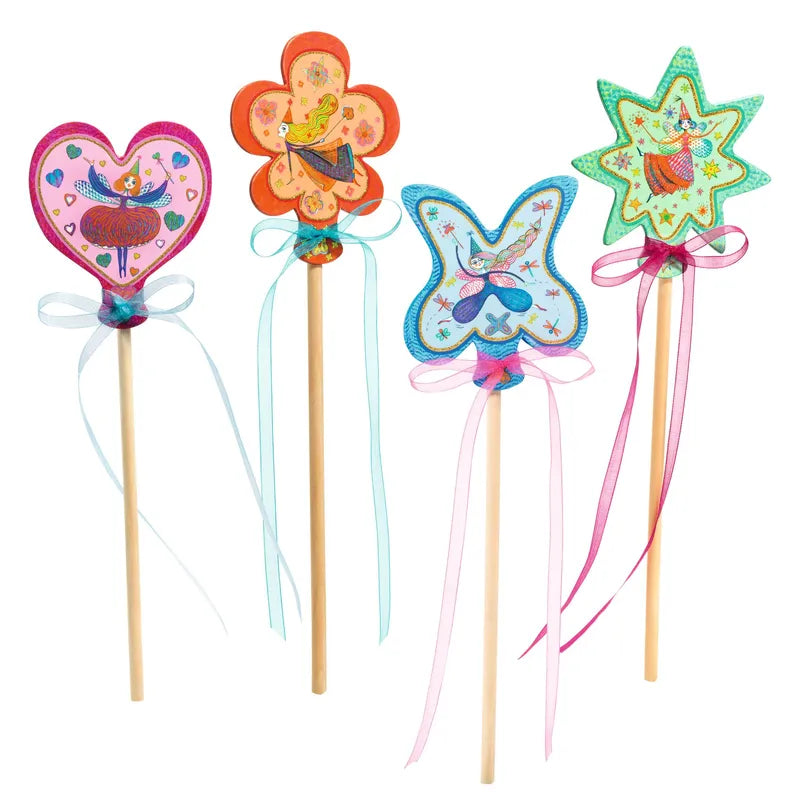 The Djeco Create Little Fairies kit features four colorful wands with wooden handles and ribbons, topped with a heart, flower, butterfly, and star. Each top is decorated with whimsical fairy illustrations and bright patterns. The ribbons come in pastel shades of blue, pink, and purple—perfect for a creative children's activity.