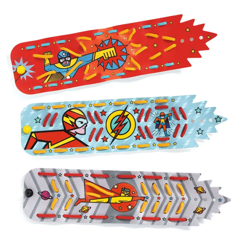 The Djeco Mosaics & Stickers Super-Powers - Fsc Mix set includes three vibrant superhero bracelets, ideal for a children's activity. The top bracelet features a red band with a superhero and explosion design; the middle bracelet highlights a blue band decorated with a superhero and lightning bolt motif; and the bottom bracelet showcases a gray band illustrating a superhero flying through the air. This creative kit promises plenty of fun!