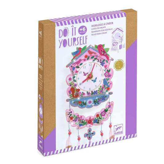 The Djeco Create Do It Yourself Clock Cuckoo is a DIY kit for ages 6+, featuring a colorful flower and bird design with sparkly details. The purple and brown packaging showcases the completed clock adorned with decorative pendulums.