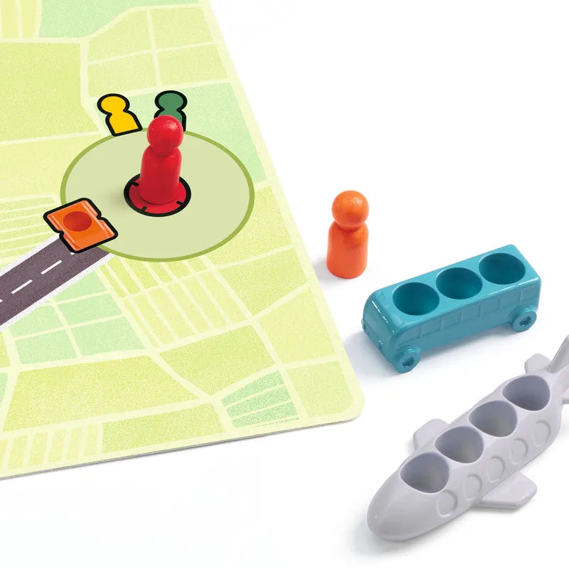 The Djeco Sologic Traffic Logic game setup includes a map with colored pegs, featuring a red peg in a circular area and a small square orange token on the road. Nearby, blue bus and gray airplane pieces are positioned on the white surface, while challenge cards offer levels of increasing difficulty.