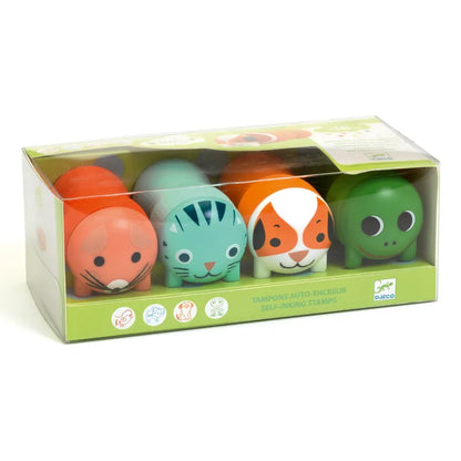 A box of self-inking "Djeco Stamps Stamps For Little Ones - Garden Animals" featuring cute animal faces, including a red fox, a blue cat, an orange dog, and a green turtle. Designed as a toy for small hands, the ergonomic handles make stamping easy. The packaging is transparent at the top and front, with a green base decorated with small icons and the brand name Djeco.