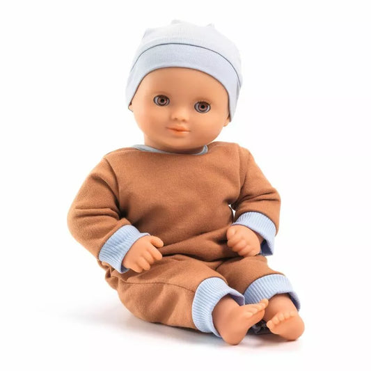 A Djeco Baby Praline Baby Doll sitting on a white surface.