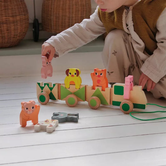 A child is playing with the Djeco Trainimo Farm on the floor.
