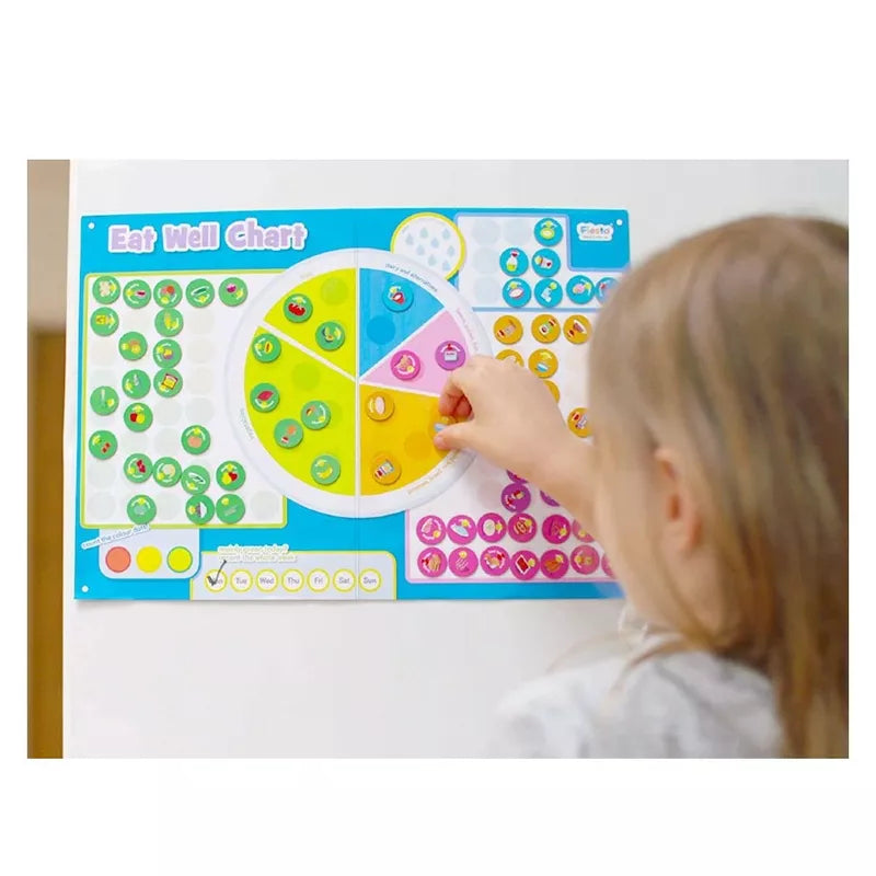 A little girl is playing with the Fiesta Crafts Eat Well Magnetic Chart.