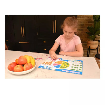A little girl sitting at a table with the Fiesta Crafts Eat Well Magnetic Chart.