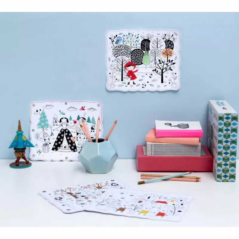 A colorful desk filled with 12 Magic Tales - To colour and hang and a variety of toys and coloring supplies.