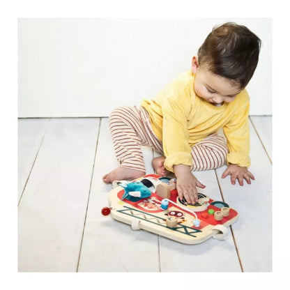 A baby playing with the Lilliputiens Fire Engine Activities Toy on the floor.