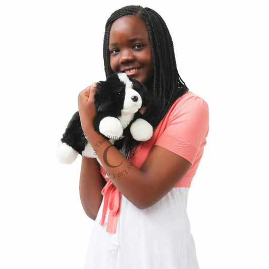 A young girl happily cuddling The Puppet Company Full-bodied Hand Puppet Border Collie.