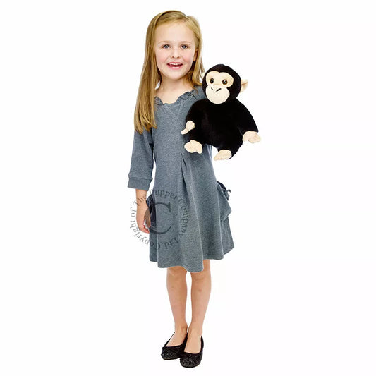 A little girl clutching The Puppet Company Full-bodied Hand Puppet Chimp.