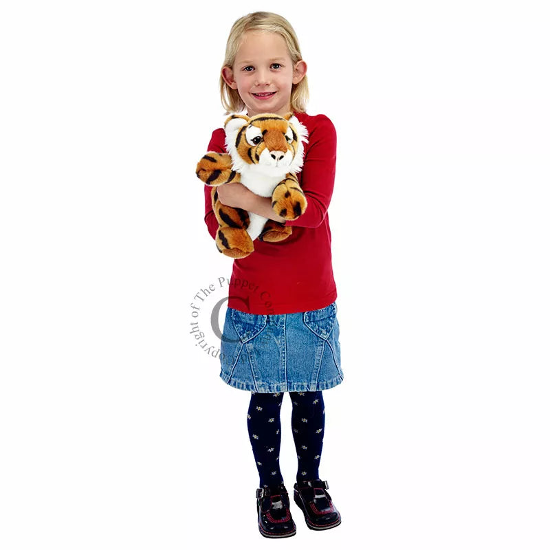 A little girl tightly clutching The Puppet Company Full-bodied Hand Puppet Tiger.