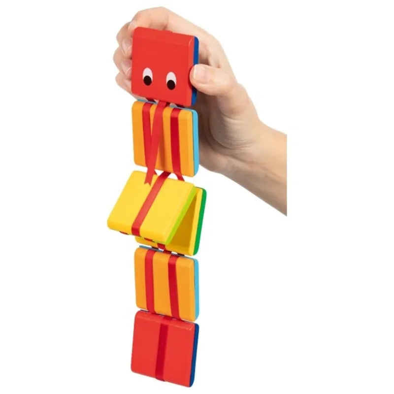 A hand holds a vibrant Jacob’s Ladder with Eyes, featuring red, yellow, orange, and green blocks connected by red ribbons. The top block has two googly eyes, giving it a playful, caterpillar-like appearance—perfect as a stocking filler for little ones.