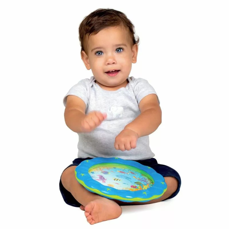 A baby sitting on the floor playing with a Halilit Wave Drum music toy.