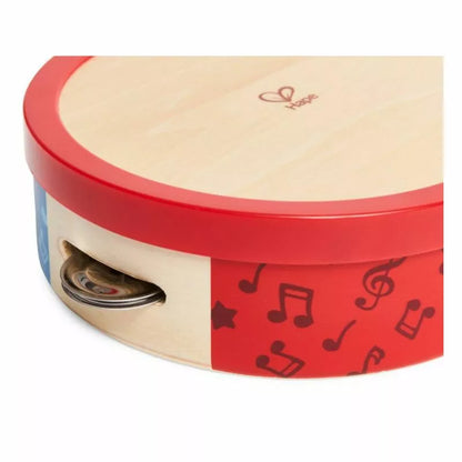 A red and white Hape Tap-along Tambourine box with musical notes on it.