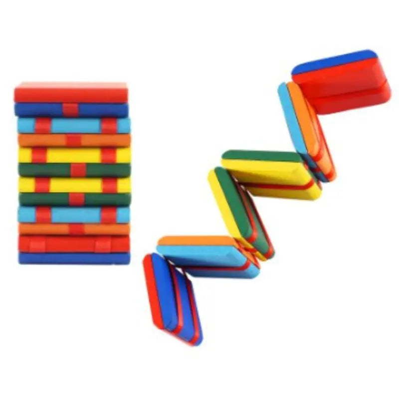 A stack of Jacob’s Ladder Game tiles stands on the left, while several toy dominoes have toppled to the right, displaying vibrant red, blue, yellow, and green colors.