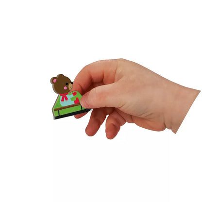 A hand holding Janod 4 Seasons Magneti’Book with a small brown bear on top.