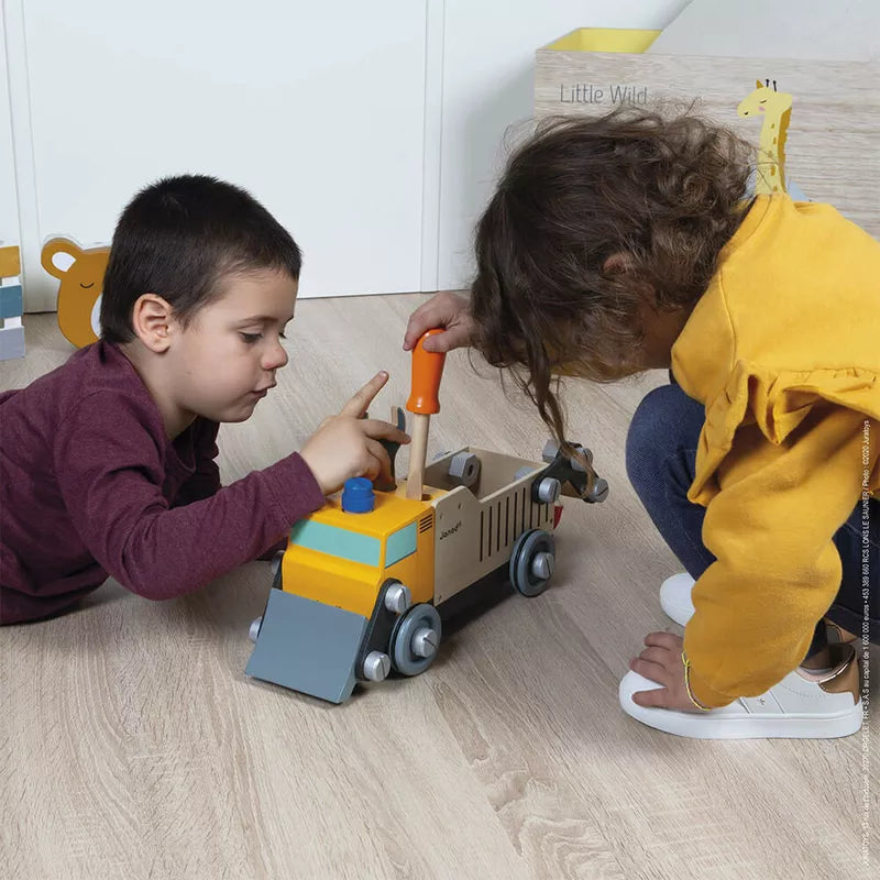 Two children playing with a Janod Brico'kids DIY Construction Truck on the floor.