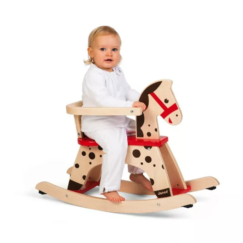 A baby sitting on a Janod Caramel Rocking Horse.