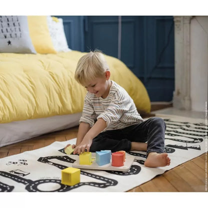 A young boy playing with Janod Essential – Volumes on the floor.