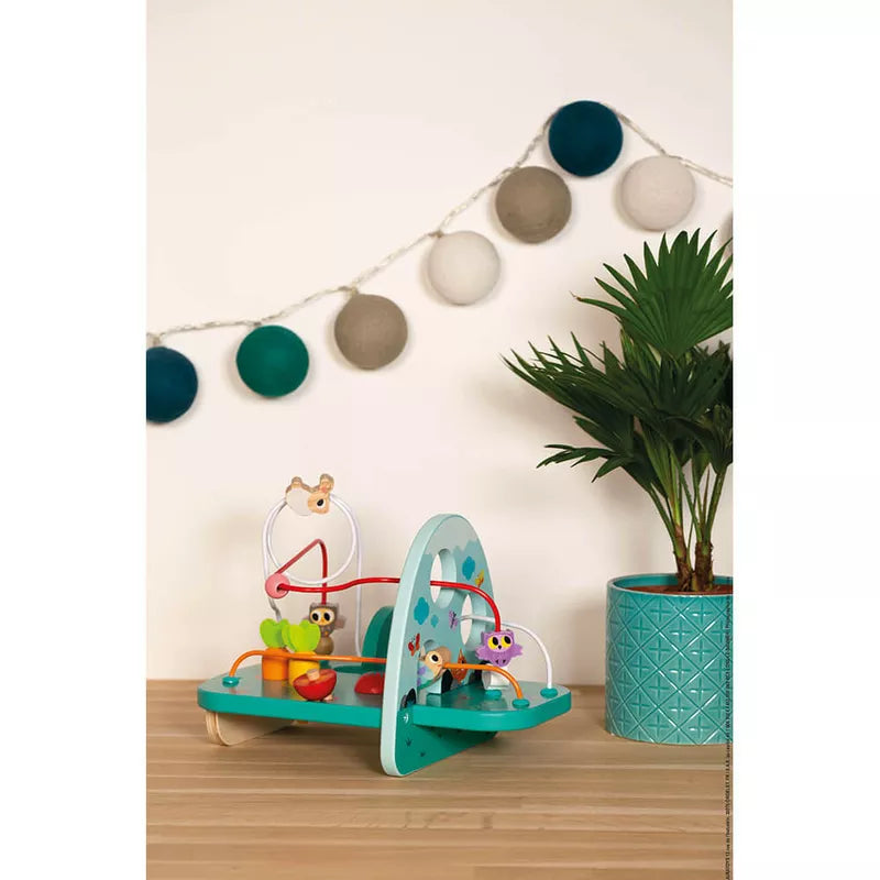 The Janod Rabbit and Co Looping Toy is on a table next to a potted plant.