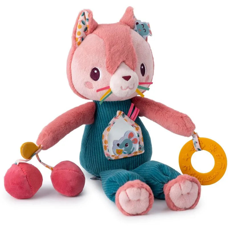 The Lilliputiens I'm Discovering Jeanne Multi-Activity Cat is a plush toy with pink fur, big eyes, and teal overalls featuring an animal patch. It holds cherries and a yellow ring, making it perfect as a baby's first toy or gift. Its ears have vibrant patterned fabric inserts.