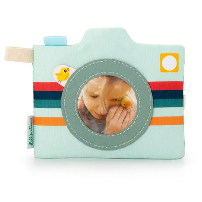 The Lilliputiens I'm Discovering Joe Photo Album is a soft, plush camera-shaped toy perfect for a baby gift. It features stripes, a chicken sticker, and has a circular window with space for displaying 'child's first toy' memories alongside a beige tag.