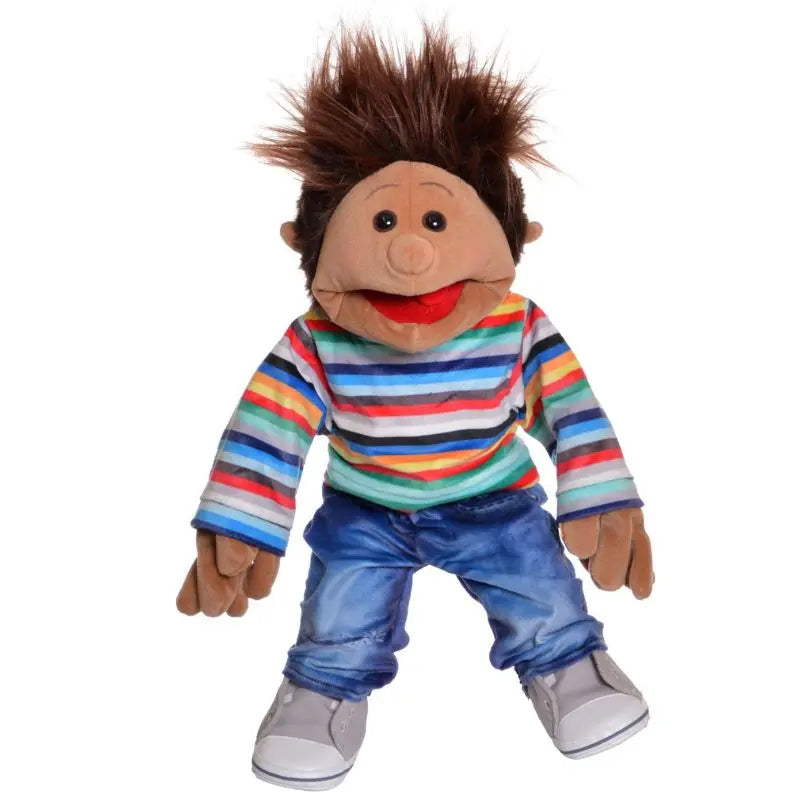 The Johann Boy Hand Puppet (45cm) features brown skin, spiky brown hair, a wide red mouth, and wears a colorful striped shirt, blue jeans, and gray shoes. Shown sitting against a white background.