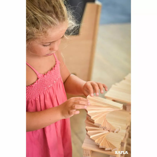 A little girl that is playing with some KAPLA® Construction 200 Planks.
