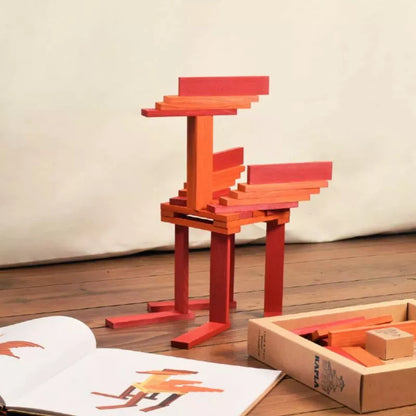 A KAPLA® 40 Coloured Planks (Orange & Red) model of a flamingo sitting next to a Book made of coloured planks.