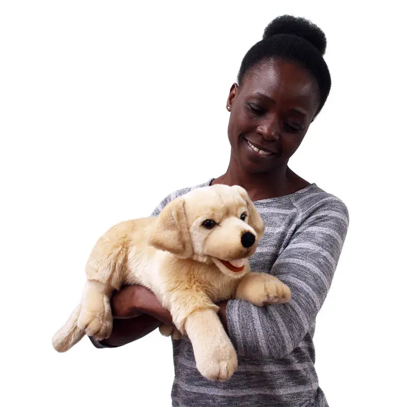 A woman in a gray striped sweater smiles while holding the Labrador Hand Puppet - Playful Puppies against a plain white background.