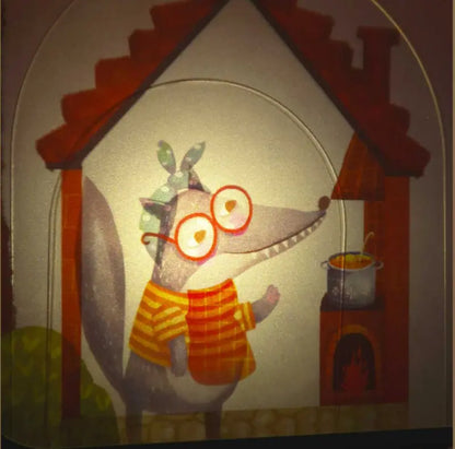 A cartoon wolf with glasses, a green headscarf, and a yellow-striped shirt stands in a house, smiling at a pot over the stove—ideal for imaginative play with Shadow Theatre – The Amazing Light Theatre of Wonders.