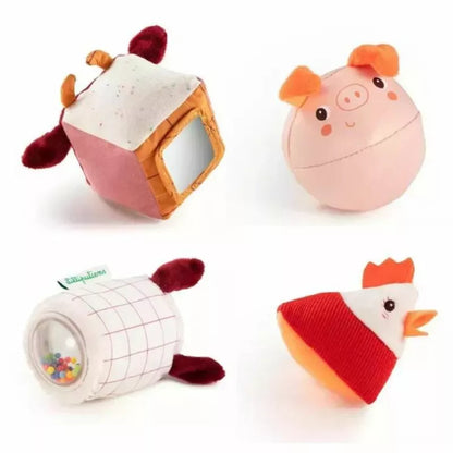 Four whimsical Lilliputiens Set of 4 Farm Shapes, each with a unique and playful design: a spotted cow cube, a cheerful pig ball, a lamb rattle wrapped in a cozy blanket, and a bright