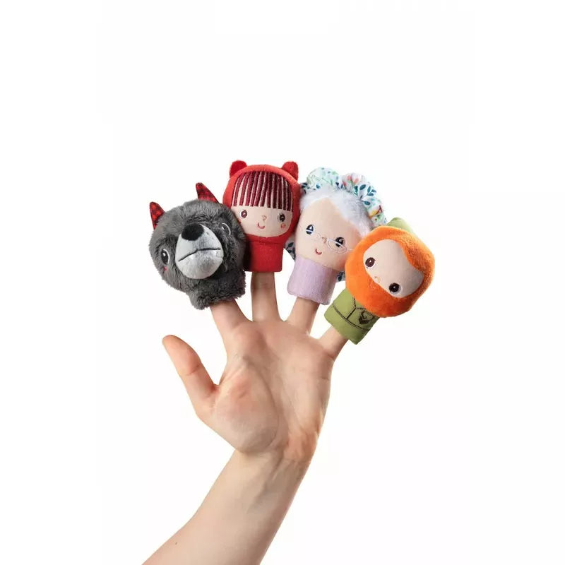 A hand holding a collection of Lilliputiens Little Red Riding Hood Finger Puppets, including an animal, some cute, colorful characters, and a toy puppet inspired by the Little Riding Hood fairytale.