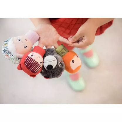 A child holding a collection of colorful toy finger puppets from the Lilliputiens Little Red Riding Hood Finger Puppets fairytale.