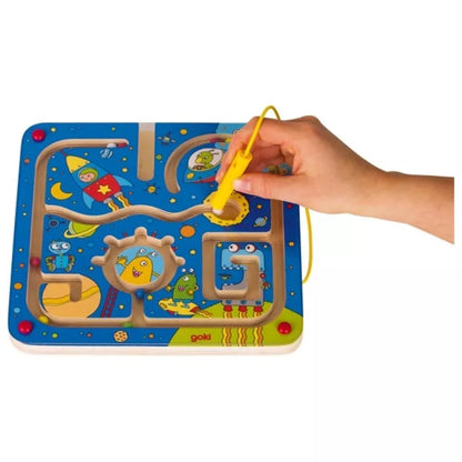 A child's hand holding a Magnetic Maze Board Space over a blue play mat.