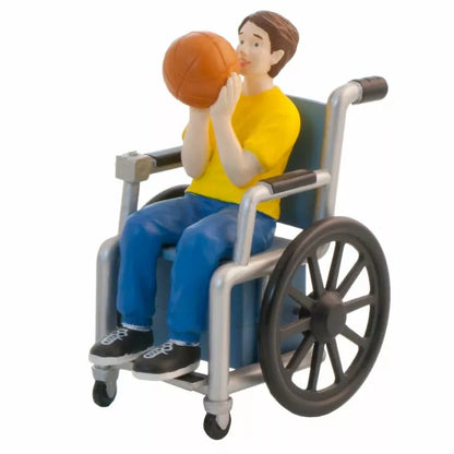 A plastic figurine of a man in a wheel chair holding a basketball.