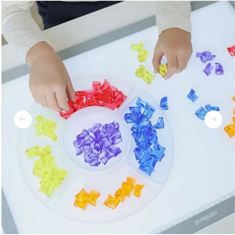 A child is playing with Miniland Translucent Counting Gems.