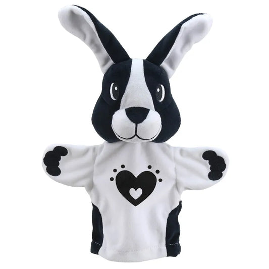 A hand puppet in the shape of My First Black & White Puppet Rabbit with a black and white face, large ears, and wearing a white shirt with a black heart design on it.