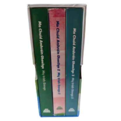 A box set titled "Bailiúchán Mo Chuid Amhráin Ghaeilge" with three green and pink Irish children's songbooks, upright in a white case—the ideal addition to any My Irish Books box set collection.
