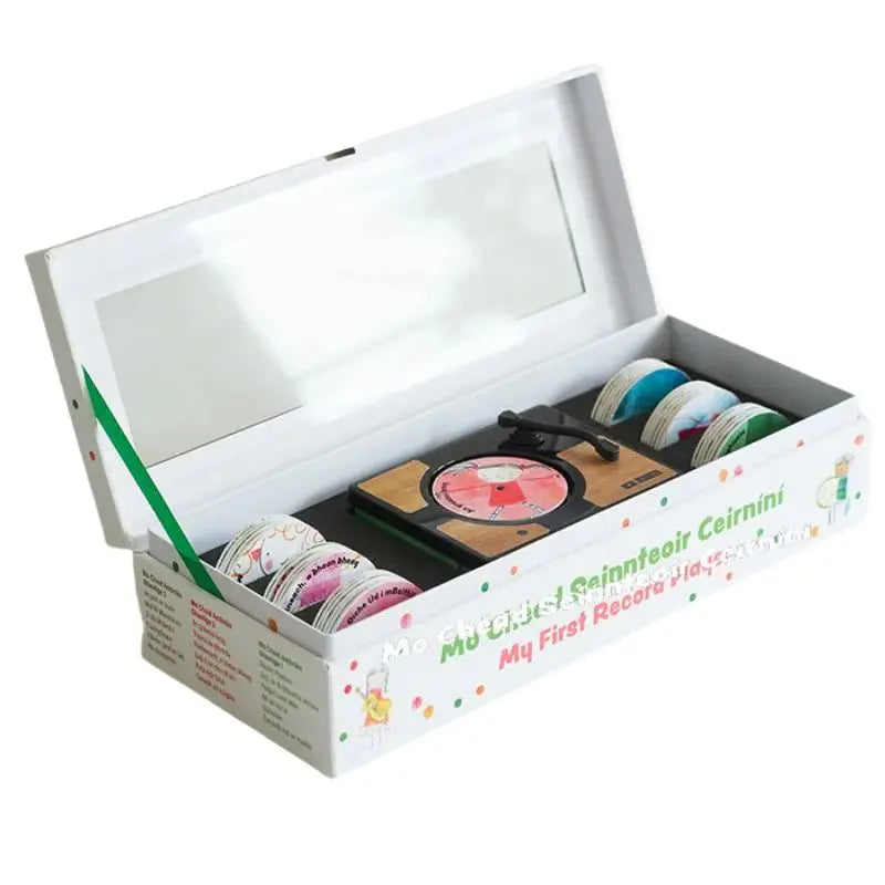 A white box with a clear lid holds a Mini Gramophone, plus colorful tape rolls. Labeled “Mini Gramophone Box Set” in English and Irish, it’s perfect for introducing kids to traditional Irish songs.