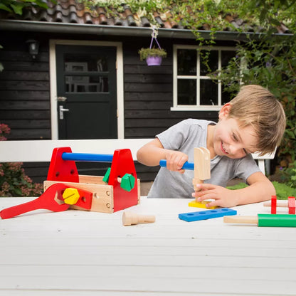 A young boy playing with the New Classic Toys Tool Kit on a table.