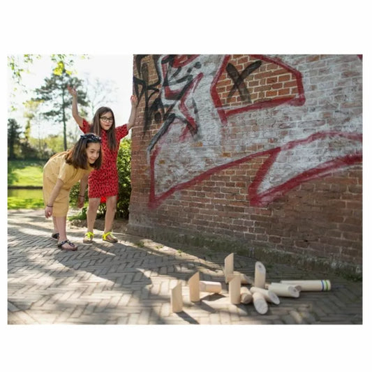 Two young girls playing Buitenspeel Finnish Throwing Game next to a brick wall.