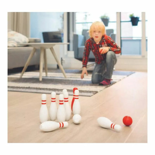 A young boy playing with Buitenspeel Wooden Bowling Red and White on the floor.