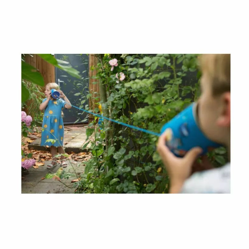 A little girl in a blue dress holding a Buitenspeel Tin-o-Phone.