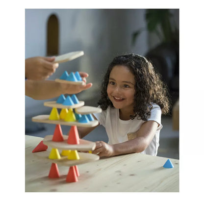 A little girl playing with a Piks Construction Big Kit – 64 pieces tower of wooden toys.