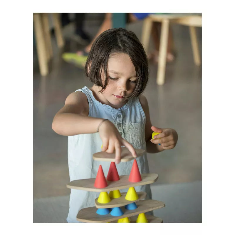 A little girl playing with a tower of Piks Construction Small Kit wooden toys.